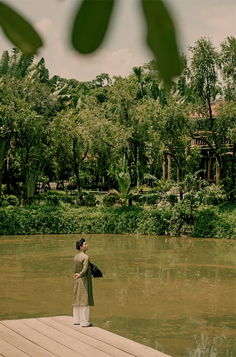 Persona mirando serenamente hacia un lago verde rodeado de árboles tropicales, simbolizando la tranquilidad y el ritmo pausado de los viajes diseñados por nuestra agencia boutique.